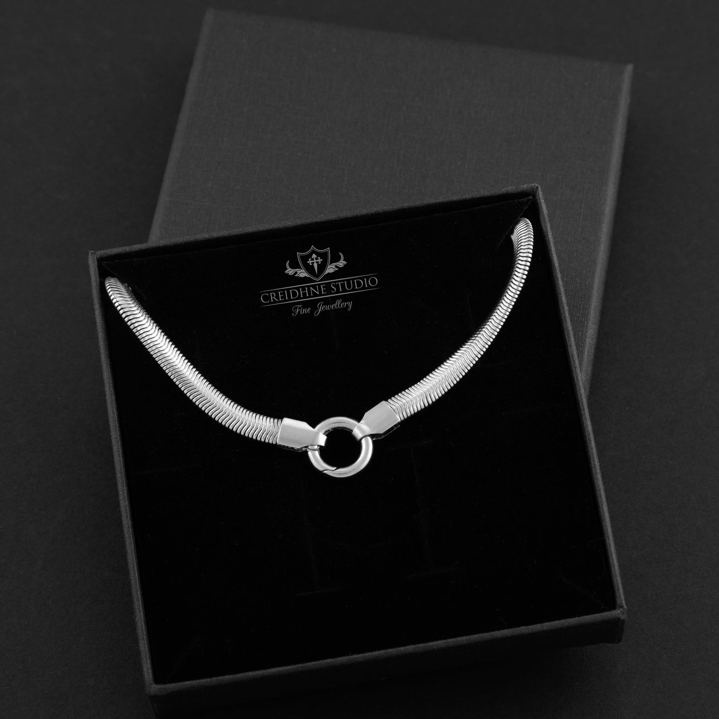 Silver snake chain necklace in a black box with 'Creidhne Studio' branding.