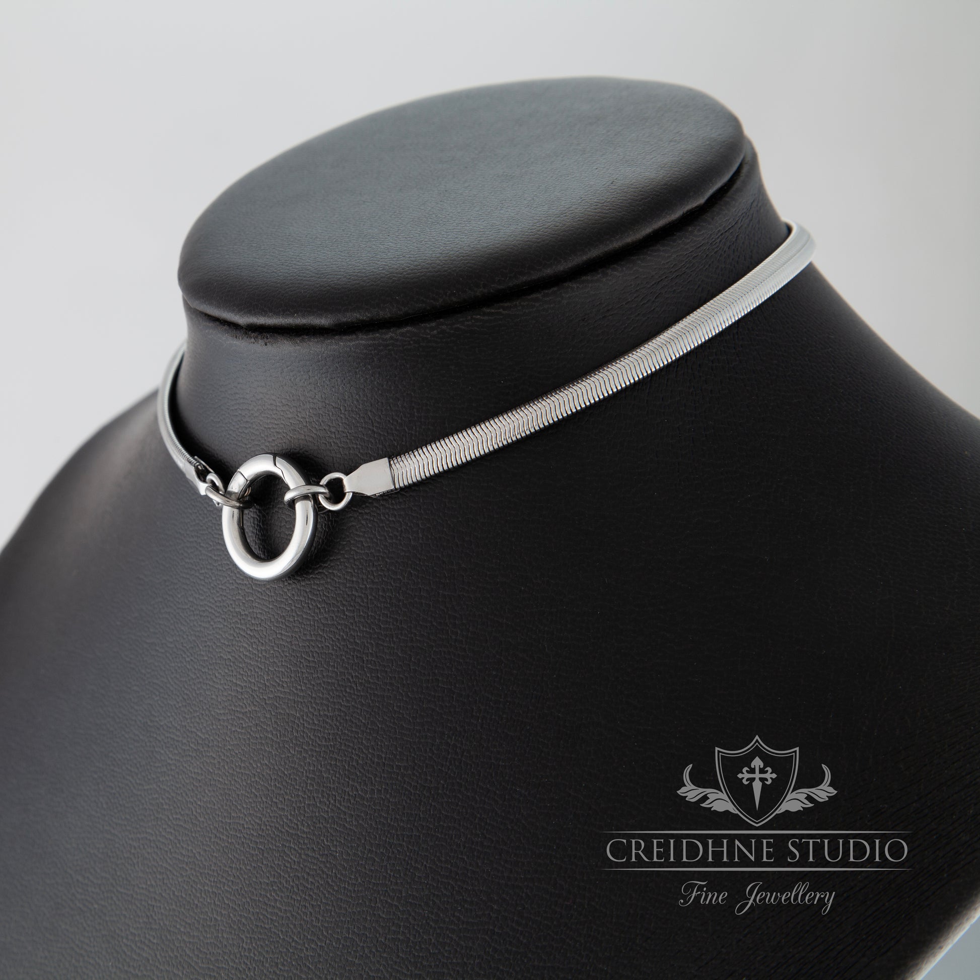 Side view of silver snake chain collar black leather mannequin, Creidhne Studio logo