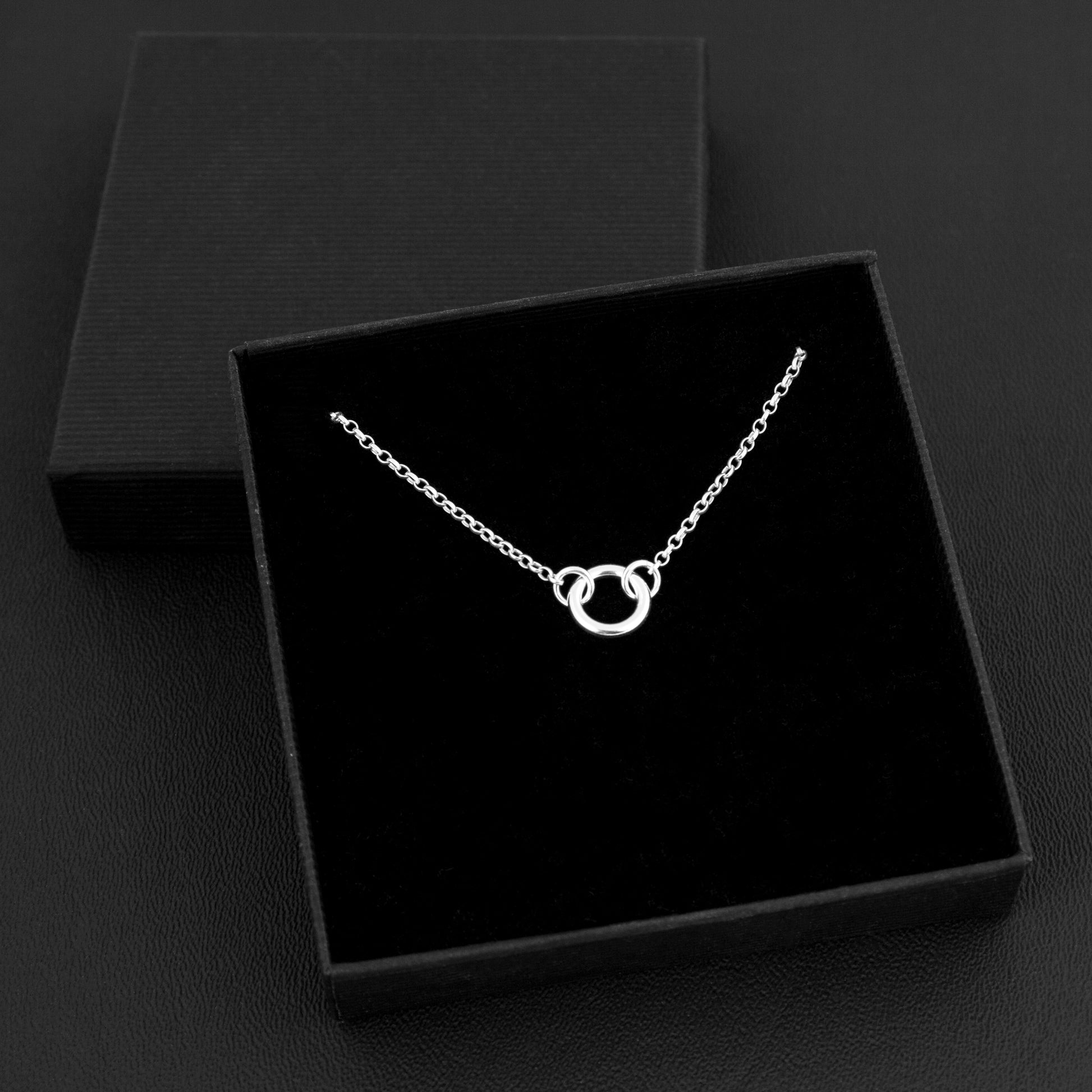 Silver day collar consisting of a delicate silver chain with a tiny 10mm diameter O ring suspended in the centre. The O ring is made of 1.8mm thick silver wire. Shown in a box